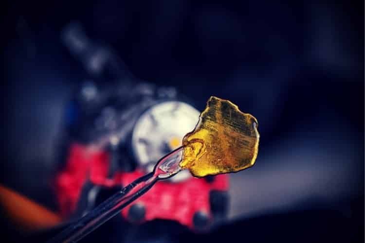 Cannabis oil concentrate aka shatter (train wreck strain) with dabbing tool against dark background Cannabis oil concentrate aka shatter (train wreck strain) with dabbing tool against dark background