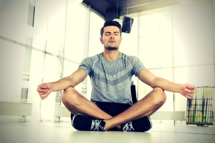 Man meditating in fitness gym