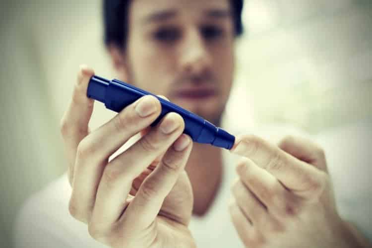 Man using lancelet on finger in bathroom close up