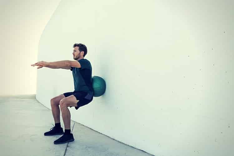 Strength training man doing medicine ball squats.